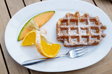 tasty waffles with fruit decoration on white plate