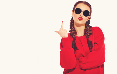Portrait of young happy smiling woman model with bright makeup and colorful lips with two horns and sunglasses in summer red clothes isolated on white. Going crazy and showing fuck off sign