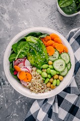 Vegan Buddha bowl salad with spinach, quinoa, roasted chickpeas, grilled chicken, avocado, edamame beans, cucumbers, sesame and pumpkin seeds.