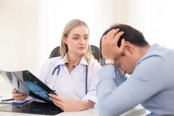 Fototapeta premium Attractive female doctor showing x-ray films to patient at clinic. Medical and Health care concept.
