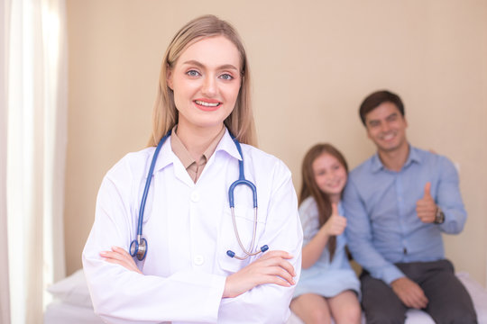 Attractive female doctor looking to camera in front of patient at clinic. Medical and Health care concept.