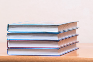 A stack of books on a light background. Four books in a pile