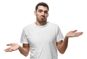 I don't know. Young man isolated on white background, showing helpless gesture with arm and hands, mouth curved as if he does not know what to do