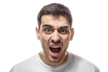 Closeup shot of furious shouting man standing isolated against white backgroung and screaming desperately. What have you done concept