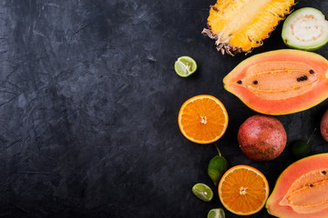 Tropical fruits, papaya, pineapple, passion, guava, lime and orange  on dark background, top view