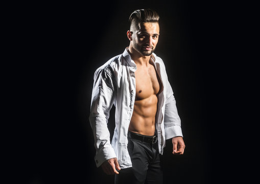Man. Guy in a white shirt on a black background. Young businessman with a stylish hairstyle. Male model. Athlete from a beautiful strong body in an informal setting. Beautiful young man's face