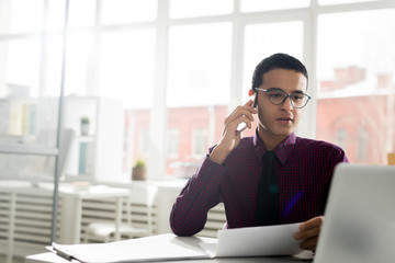 Businessman working with papers and laptop and discussing work on the phone