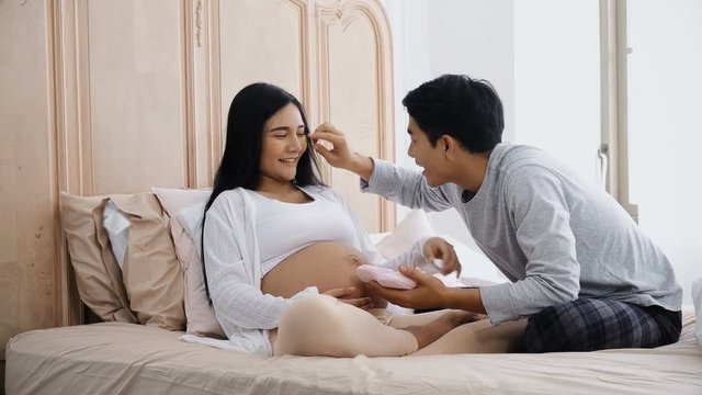 The parent talking and playing little shoes on belly pregnant