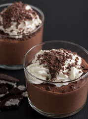 Chocolate mousse in a glasses on a black stone background.