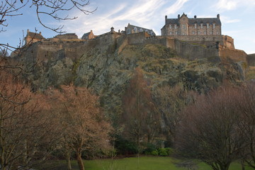 Zamek w Edynburgu, Szkocja, na wysokim skalnym wzgórzu, widok z dołu, u podnóża wzniesienia wierzchołki drzew w parku