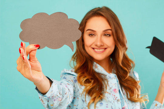 Young woman holding two empty thought bubbles near her head over blue background