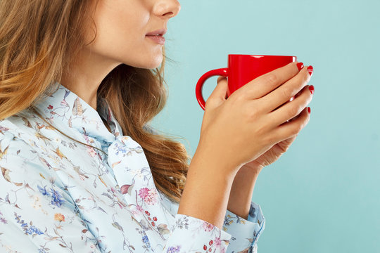 Young woman holding a cup of tea or coffee over blue background