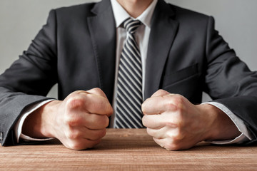 Angry businessman with closed fists on the table.
