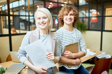 Happy young designers in smart casual looking at camera while working in office
