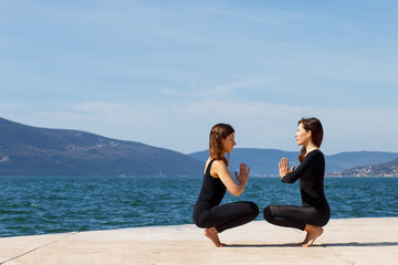 Two girls on the beach doing yoga on a pair, Montenegro