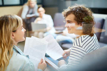 Fototapeta premium Two young financiers in casualwear consulting about details of contract at meeting