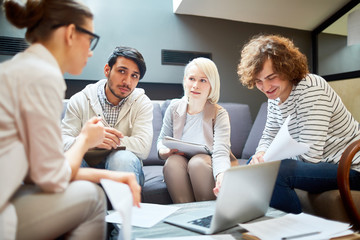Confident blonde woman looking at one of colleagues while making presentation of online project