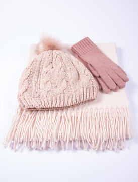 Warm winter knitted clothes - hat, scarf, gloves on a white background.