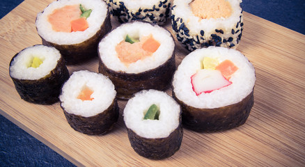 Various kinds of sushi on the wooden background.