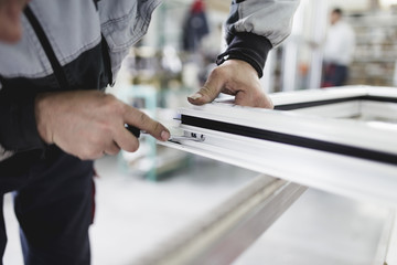 Obraz premium Manual worker assembling PVC doors and windows. Manufacturing jobs. Selective focus. Factory for aluminum and PVC windows and doors production.