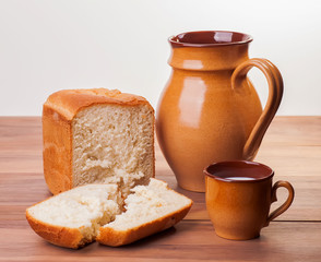 steaming fresh bread mug with milk on a wooden background