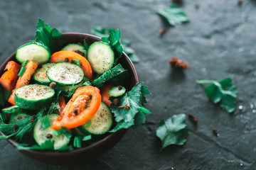 Fresh salad with vegetables on a black matte background. The concept of a healthy diet