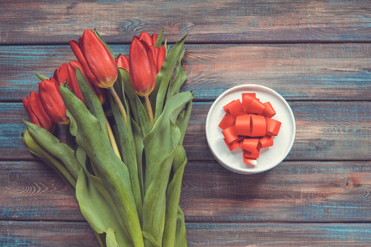 Red tulips and gift on a wooden backround