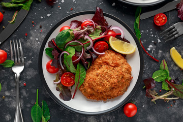 Breaded Chicken Kiev breast stuffed with butter, garlic and herbs served with vegetables in a plate.