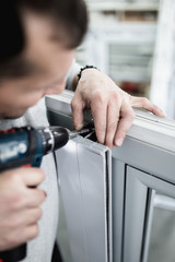 Obraz premium Manual worker assembling PVC doors and windows. Manufacturing jobs. Selective focus. Factory for aluminum and PVC windows and doors production.