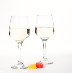 Two glasses and a bottle of white wine, on a white background near a handful of grapes