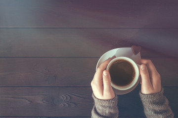 Baby girl hands with a cup of coffee on a wooden background top view flat lay