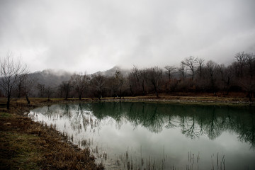 Landscape with misty morning fog in the Forest Lake or Beautiful forest lake in the morning at winter time. Azerbaijan nature.