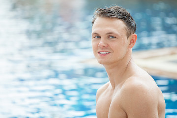 Outdoor portrait of handsome man posing at swimming pool