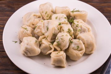 Pelmeni home-style with meat, are served with sour cream and greens