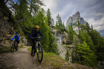 Naklejka premium Mountain biking couple with bikes on track, Cortina d'Ampezzo, Dolomites, Italy
