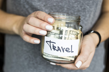 A woman is holding a piggy bank for travel full of dollars. Accumulation of finance concept