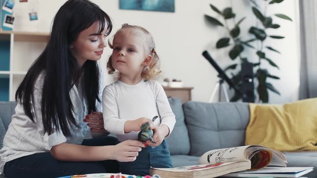 mother hug kiss little daughter painting paper together talking kid family hobby baby design love person girl house coloring mom play art paintbrush childhood happy home table artist closeup