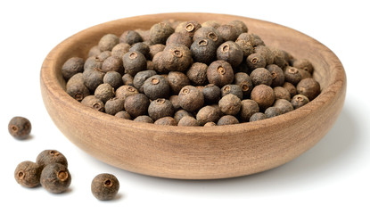 dried herb, allspice in the wooden plate. isolated on white