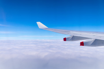 Fototapeta premium Flying into blue sky and sea of clouds and Wing of airplane with skyline top view as look from window airplane, during flight space for text message, frame or traveling idea concept