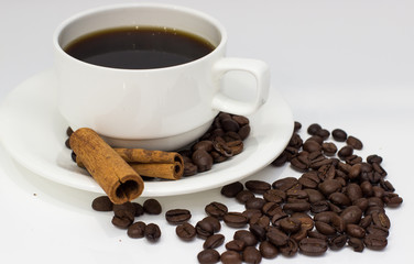 Grains of coffee and cinnamon sticks on white background