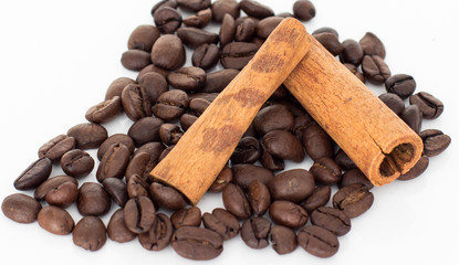 Grains of coffee and cinnamon sticks on white background