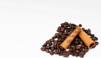 Grains of coffee and cinnamon sticks on white background