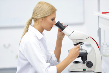 Portrait of a young scientist using a microscope in a lab