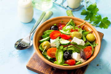 Summer vitamin salad. Greek salad with fresh vegetables, feta cheese and black olives on a blue stone or concrete table. Diet, concept of vegetarian food.