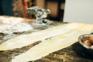 Pasta machine, dough and eggs on kitchen table