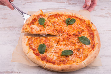 A pizza piece on a paddle with spinach