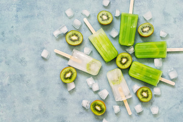 Six portions of frozen kiwi juice on a stick, halves kiwi on a blue background. Frozen fruit juice. The view from the top,place for text.