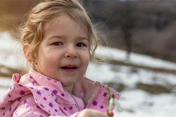 portrait of little child picking snowdrop flowers in spring .