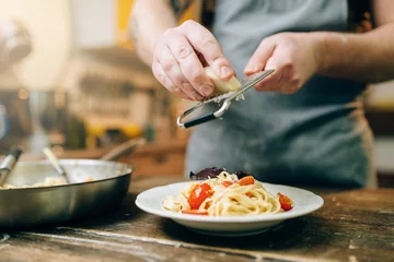 Tuinposter Chef grates cheese to the plate with fresh pasta © Nomad_Soul