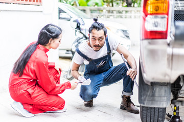 Fixing car engine in automobile repair garage. Handsome mechanics in uniform are repairing car while working in auto service